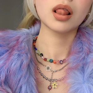 Détail du collier superposé Y2K avec perles florales colorées et pendentif fleur en verre