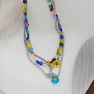 Gros plan de fleurs colorées en verre millefiori et collier de perles argentées multicouche