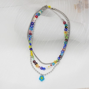 Détail d'un collier bohème multicouche avec perles de verre colorées et pendentif fleur bleue
