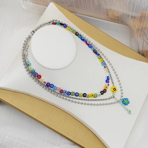 Détail de colliers superposés avec perles de millefiori et charmes de fleurs bleues