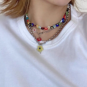 Gros plan d'un collier à trois rangs avec perles colorées et pendentif fleur jaune