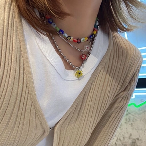 Détail d'un collier Y2K à plusieurs rangs avec perles florales et pendentifs fleurs argentés