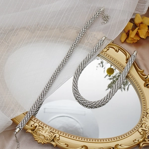 Détail d'une parure de bijoux argentés avec collier et bracelet en strass sur miroir