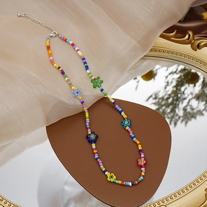 Detalle de collar bohemio de cuentas de colores con flores sobre tela de seda beige