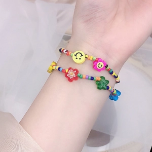 Detalle de dos pulseras de cuentas coloridas con dijes de cara sonriente, flor y estrella