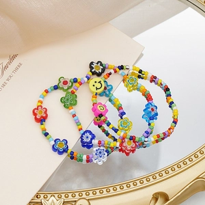 Detalle de collar de cuentas coloridas con colgantes de flores y emoticonos en un espejo