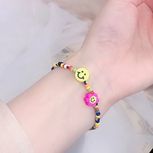 Primer plano de collar de cuentas coloridas con carita sonriente y flores en modelo