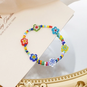 Detalle de collar de cuentas coloridas con dijes de flores translúcidas sobre fondo