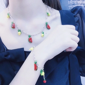Détail d'un ensemble de chaînes argentées avec breloques de fruits en verre sur mannequin