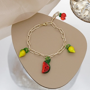 Détail du bracelet à maillons dorés avec breloques colorées en forme de fruits