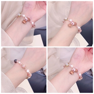 Close-up of rose quartz, freshwater pearl, and crystal bead bracelet with metal charms