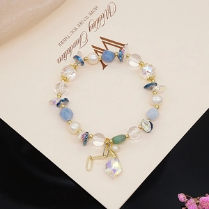 Detail of bead bracelet with teardrop crystal pendant on wedding invitation background