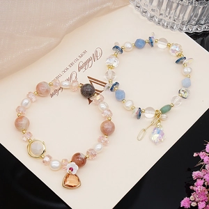 Detail of rose quartz and aquamarine beaded bracelets with pearls and metal charms