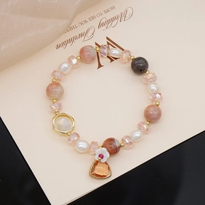 Macro detail of sunstone, pearl, and crystal beaded bracelet with golden charms