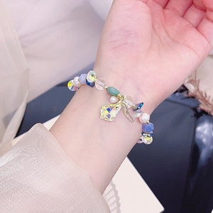 Detail view of pink crystal, aquamarine, and pearl beaded bracelet with a yellow charm