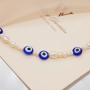 Vista macro detallada del collar de perlas barrocas con cuentas de ojo azul para hombres y mujeres