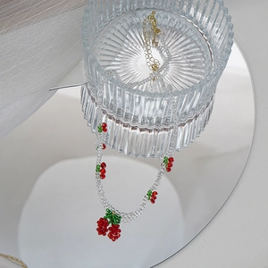 Vue détaillée du collier de cerises perlé à la main avec perles de cristal sur miroir