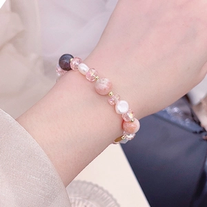 Detail view of pink rose quartz and freshwater pearls on an adjustable elastic bracelet