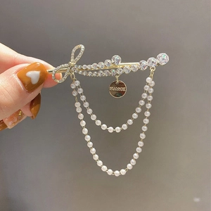 Detail van de gouden haarspeld met strass strik en elegante parelmoer franjes