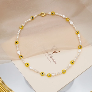 Detalle de collar de perlas barrocas con cuentas de ojo de diablo amarillas y cierre dorado