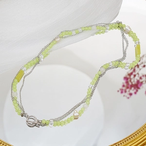 Detailed view of layered necklace with green beads, pearls, and silver OT toggle clasp