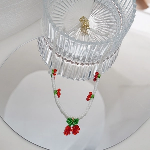 Gros plan artistique du collier de cerises perlé avec reflet sur miroir et verre