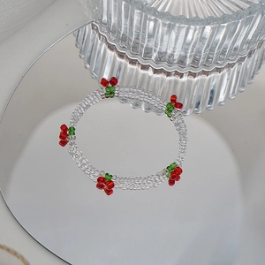 Détail du bracelet perlé avec cerises rouges sur des perles de cristal à trois rangs