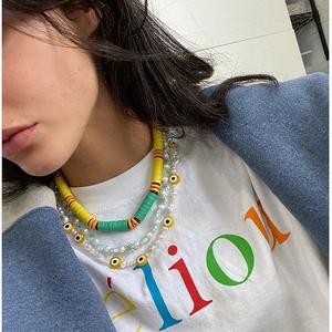 Detalle de collares bohemios en capas con cuentas de arcilla de colores y perlas de mal de ojo