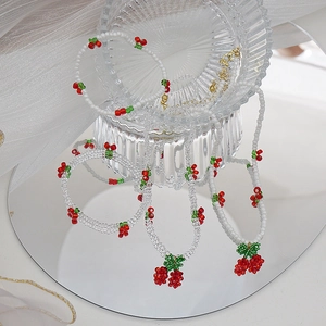 Détail du collier et bracelet en perles avec motifs de cerises faits à la main
