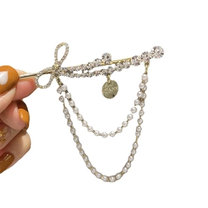Elegante gouden haarklem met strass strik en bungelende witte parel kwastje kettingen