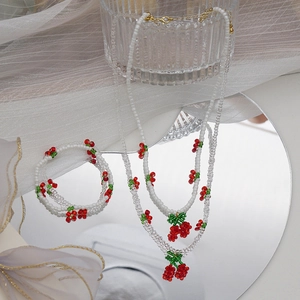 Détail du lot de colliers et bracelets en perles cerises avec accents floraux cristal