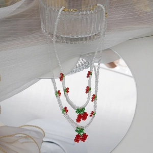 Vue détaillée de colliers de perles cerises avec cristaux blancs et transparents et fermoir doré