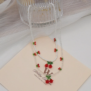 Détail du collier de cerises avec perles blanches, perles de cristal et fermoir mousqueton doré