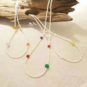 Conjunto de collar de perlas y ágata colorida sobre madera con fondo de arena natural