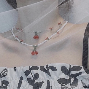 Gros plan d'un collier de perles cerise à double couche avec pendentifs en cristal rouge