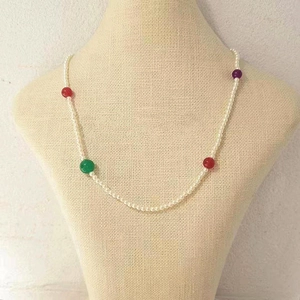 Detalle de collar de perlas blancas y piedras de ágata de colores en un busto