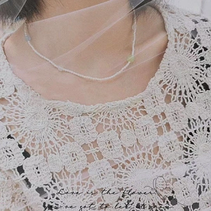 Detalle del collar de perlas con ágatas de colores sobre un fondo de encaje blanco