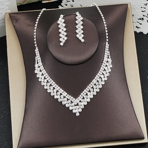 Macro shot of silver-colored V-shaped necklace and drop earrings with white rhinestones