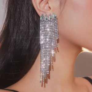 Detail of silver tassel rhinestone earrings with teardrop gems on a female model