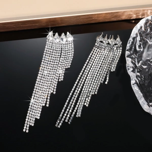 Macro detail of silver tassel earrings featuring sparkling rhinestones on black background