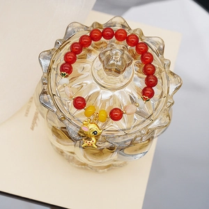 Detail eines Achat-Armbands mit goldenem Hirsch-Anhänger auf einem Glasdeckel