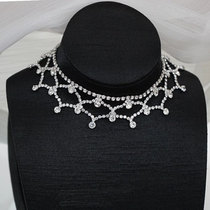 Détail d'un collier en résille de strass argentés avec motifs dentelle et cristaux pendants