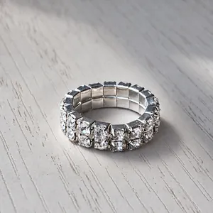 Detailed close-up of double row silver rhinestone stretch ring on grey wood surface