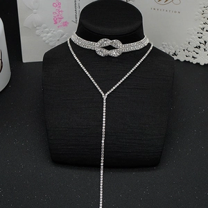 Gros plan du collier ras de cou en strass argenté avec nœud en cristal sur fond velours