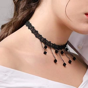 Détail du ras-du-cou en dentelle noire avec pendentifs carrés et chaînes dorées sur modèle