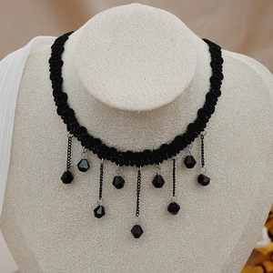 Gros plan d'un choker tressé noir avec des pendentifs en cristal noir en cascade