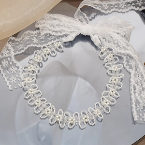 Dettaglio macro del choker in pizzo bianco e perle con elegante motivo floreale