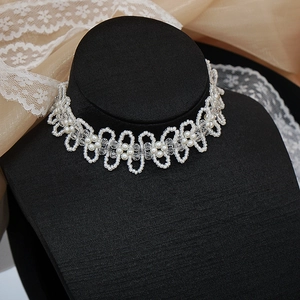 Dettaglio choker di perle con lavorazione a onde su busto da esposizione nero