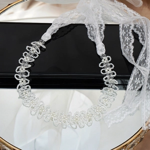 Dettaglio della collana in pizzo con perle e cristalli e nastro di fiori bianchi fatti a mano