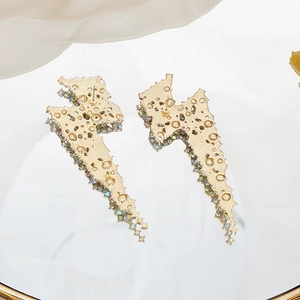 Detailed close-up of long gold lightning bolt earrings with colorful sparkling rhinestones